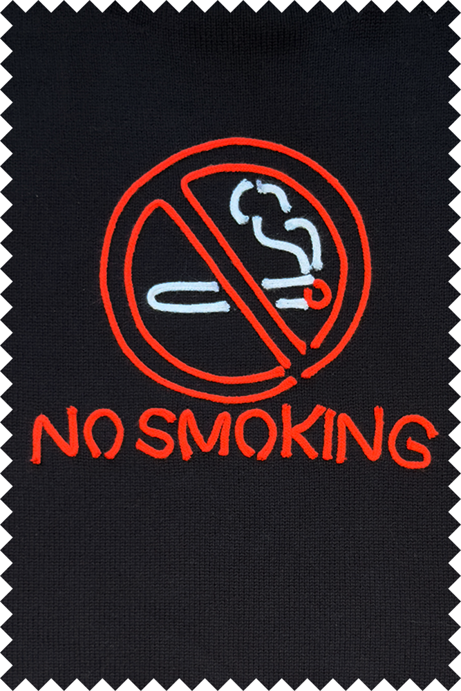 A close-up of a black woven textile with a zigzag cut edge, featuring a red and white embroidered no smoking symbol and the words 'NO SMOKING' in red.